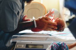Newborn baby being placed on a scale by a nurse
