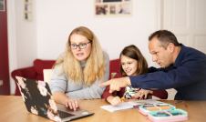 Mom and dad sitting at table with daughter helping with homework