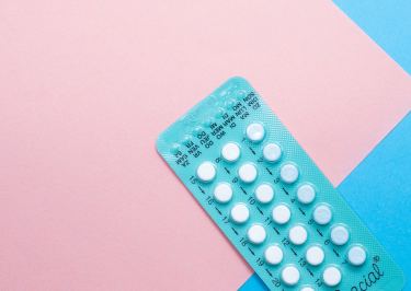 birth control pills on pink and blue background
