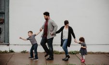 Family walking on a sidewalk in front of a white wall