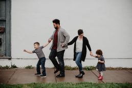 Family walking on a sidewalk in front of a white wall