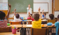 children raising their hands in a classroom at school