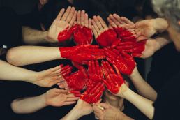 Hands forming a red heart on a black background
